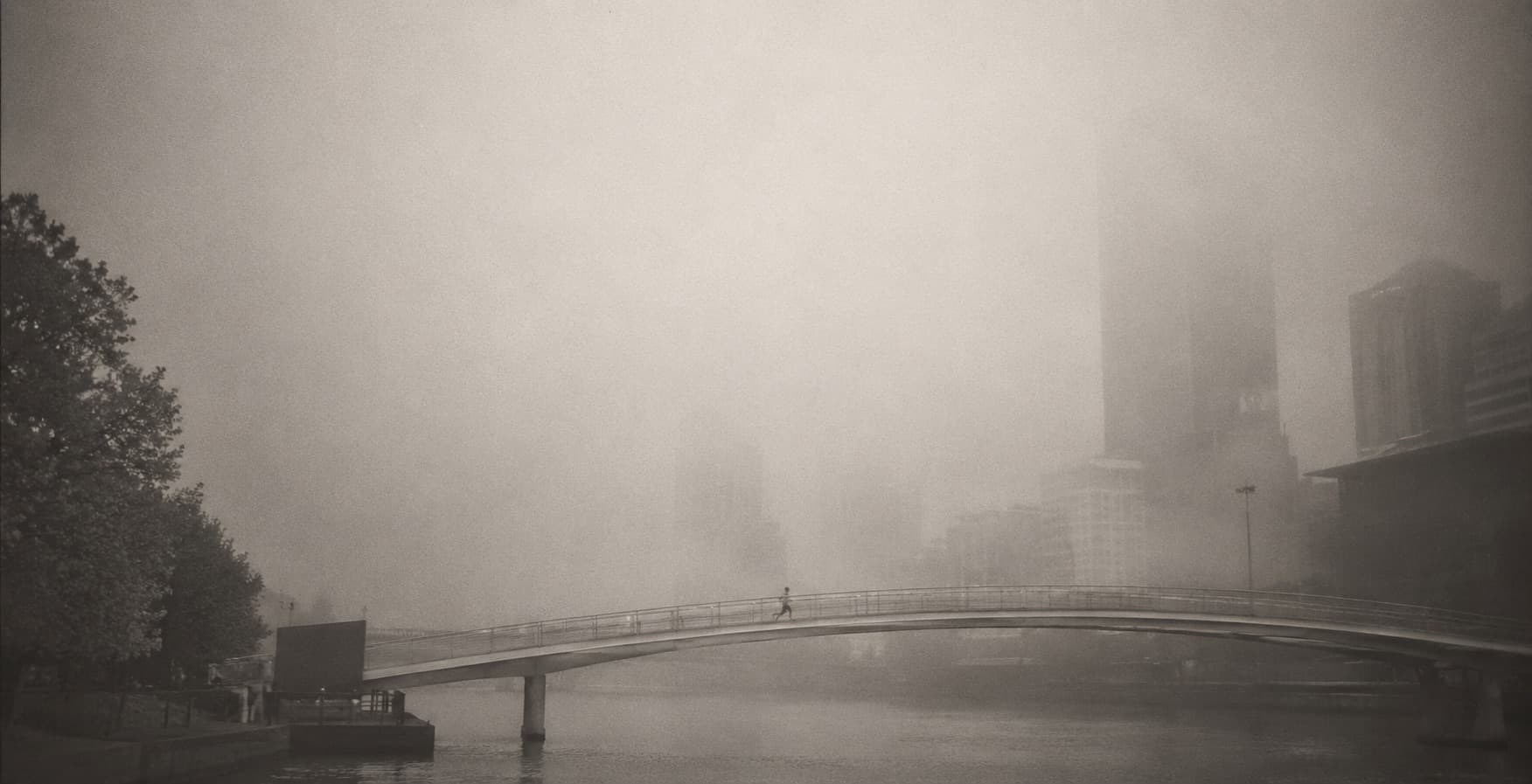 Runners crossing a bridge in morning fog